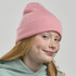 A pink ribbed beanie worn by a girl with red hair and freckles, featuring a logo on the side.
