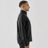 A side view of a men's black softshell jacket featuring a zip closure and pockets, with a logo on the chest.