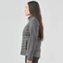 A woman stands sideways wearing a grey Women's Appalachian Thermal Softshell Jacket. The jacket features a quilted design and a logo.