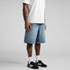 Denim shorts in a light blue wash, featuring a relaxed fit. Model wears black sneakers and white socks.