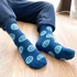 A pair of blue crew socks featuring smiling face patterns, with one sock slightly offset from the other.