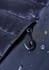 A close-up of a black soft shell jacket featuring a zippered opening and water droplets on the fabric.