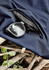 A pair of black sunglasses rests on navy lightweight shorts with a zippered pocket, placed on a textured surface.