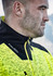 A close-up of a man wearing a bright yellow and black reinforced knit 1/2 zip pullover, featuring a branding logo.