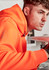 An orange unisex water-resistant hoodie with a logo, featuring a male model.