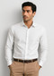 A slim fit long sleeve white button-up shirt worn with tan trousers. The shirt features a collar and has a logo.