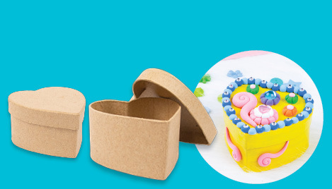 Papier mache heart gift box kit – two plain cardboard heart-shaped boxes with a decorated example covered in colourful clay on a teal background