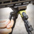 Close-up detail view of a person's hand pressing the deployment lever on an MDT GRND-POD bipod mounted to a Picatinny handguard rail