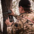Hunter wearing camouflage clothing mounting the compact cellular adapter to a forest tree trunk