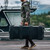 Person carrying a black Pelican Vault V730 tactical rifle hard case horizontally by dockside water