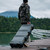 Person rolling a Pelican Vault V730 wheeled tactical rifle hard case down a wooden dock walkway outdoors
