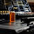 Atmospheric lifestyle shot of a small bottle of golden cleaning oil sitting upright on a dark workbench layout