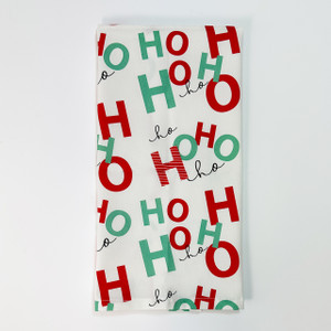 White cotton hand towel with playful red and green “Ho Ho Ho” typography pattern, folded on white background White cotton hand towel with playful red and green “Ho Ho Ho” typography pattern, folded on white background