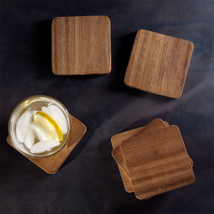 A lifestyle image demonstrating the use of the acacia coasters, with one coaster protecting a surface from a lit candle, while two other coasters from the set are placed nearby. A lifestyle image demonstrating the use of the acacia coasters, with one coaster protecting a surface from a lit candle, while two other coasters from the set are placed nearby.