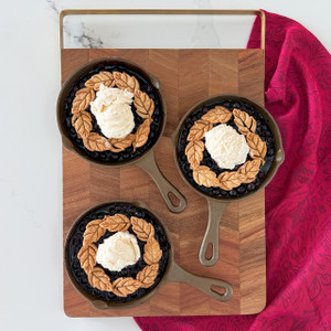 An overhead view of three individual desserts served in the mini cast iron skillets, showcasing an elegant presentation for guests. An overhead view of three individual desserts served in the mini cast iron skillets, showcasing an elegant presentation for guests.
