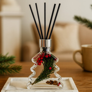 A festive Fir & Berry Christmas Tree Reed Diffuser, featuring a clear glass bottle shaped like a Christmas tree and filled with beautiful holiday botanicals like green sprigs and red berries, is elegantly styled in a cozy home setting. A festive Fir & Berry Christmas Tree Reed Diffuser, featuring a clear glass bottle shaped like a Christmas tree and filled with beautiful holiday botanicals like green sprigs and red berries, is elegantly styled in a cozy home setting.