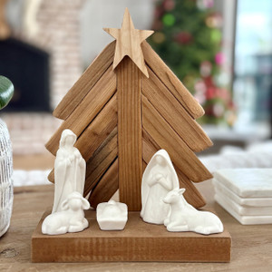Rustic wood and ceramic nativity set with star-topped driftwood tree backdrop on a wooden base; white Holy Family figures and animals Rustic wood and ceramic nativity set with star-topped driftwood tree backdrop on a wooden base; white Holy Family figures and animals