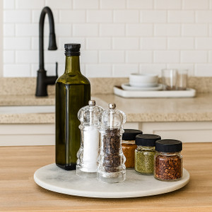 White marble lazy susan on kitchen counter holding olive oil bottle, salt and pepper mills, and spice jars White marble lazy susan on kitchen counter holding olive oil bottle, salt and pepper mills, and spice jars
