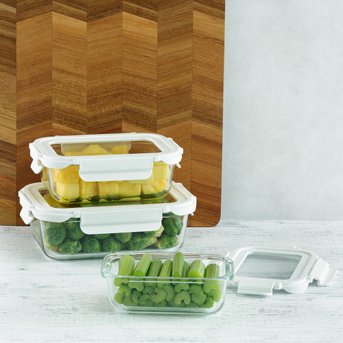 The set of three glass storage containers filled with fresh ingredients are shown in a modern kitchen setting, with two stacked to demonstrate their space-saving design.