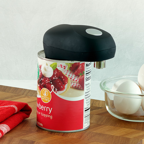 The black, non-slip automatic can opener is shown in a kitchen setting, effortlessly opening a can of strawberry pie filling with a simple one-touch operation.