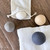 The wool dryer balls are shown with their storage pouch and a gray towel, highlighting the product's simple, eco-friendly aesthetic.
