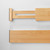 A detailed close-up of the end of a bamboo drawer divider, highlighting the non-slip grip pad and the internal spring-loaded mechanism that ensures a secure fit.