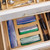 The bamboo bag organizer is shown inside a slightly open kitchen drawer filled with household items, demonstrating how it creates a tidy, clutter-free space.