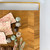 A close-up lifestyle image showing a hand gripping the sturdy matte gold handle, demonstrating the ease of carrying and serving with the elegant board.