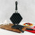 The closed Hong Kong egg waffle pan is resting on a wooden cutting board, ready for use in a kitchen setting.