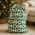 Green “HO HO HO” drawstring gift sack styled next to a Christmas tree in a cozy living room