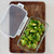 A rectangular glass baker with a lid, viewed from the side, showing stacks of food items inside, implying meal prepping or storage.