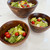 A different arrangement of three acacia wood bowls filled with colorful salads, highlighting their versatility for serving individual portions and snacks.