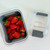 Fresh Keeper storage container disassembled—clear base, gray vented basket filled with strawberries, and adjustable-vent lid on a white background