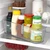Slim clear rectangular organizer bin holding condiments and jars on a refrigerator shelf, front pull handle visible
