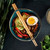 Close-up of reactive seas stoneware ramen bowl with bamboo chopsticks resting across the rim