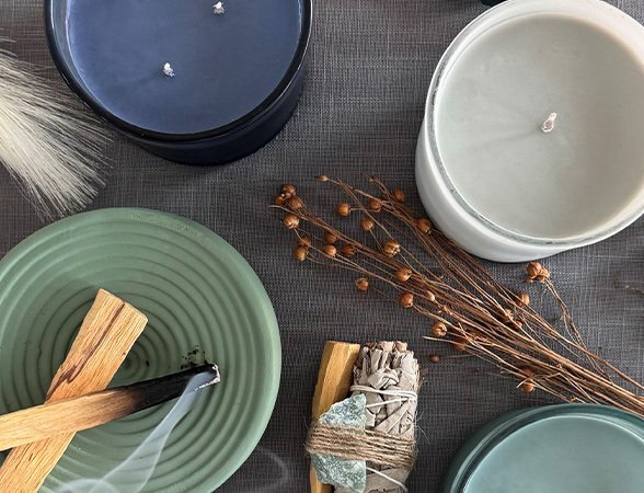 Scented candles, palo santo, and sage bundles arranged on a textured tabletop