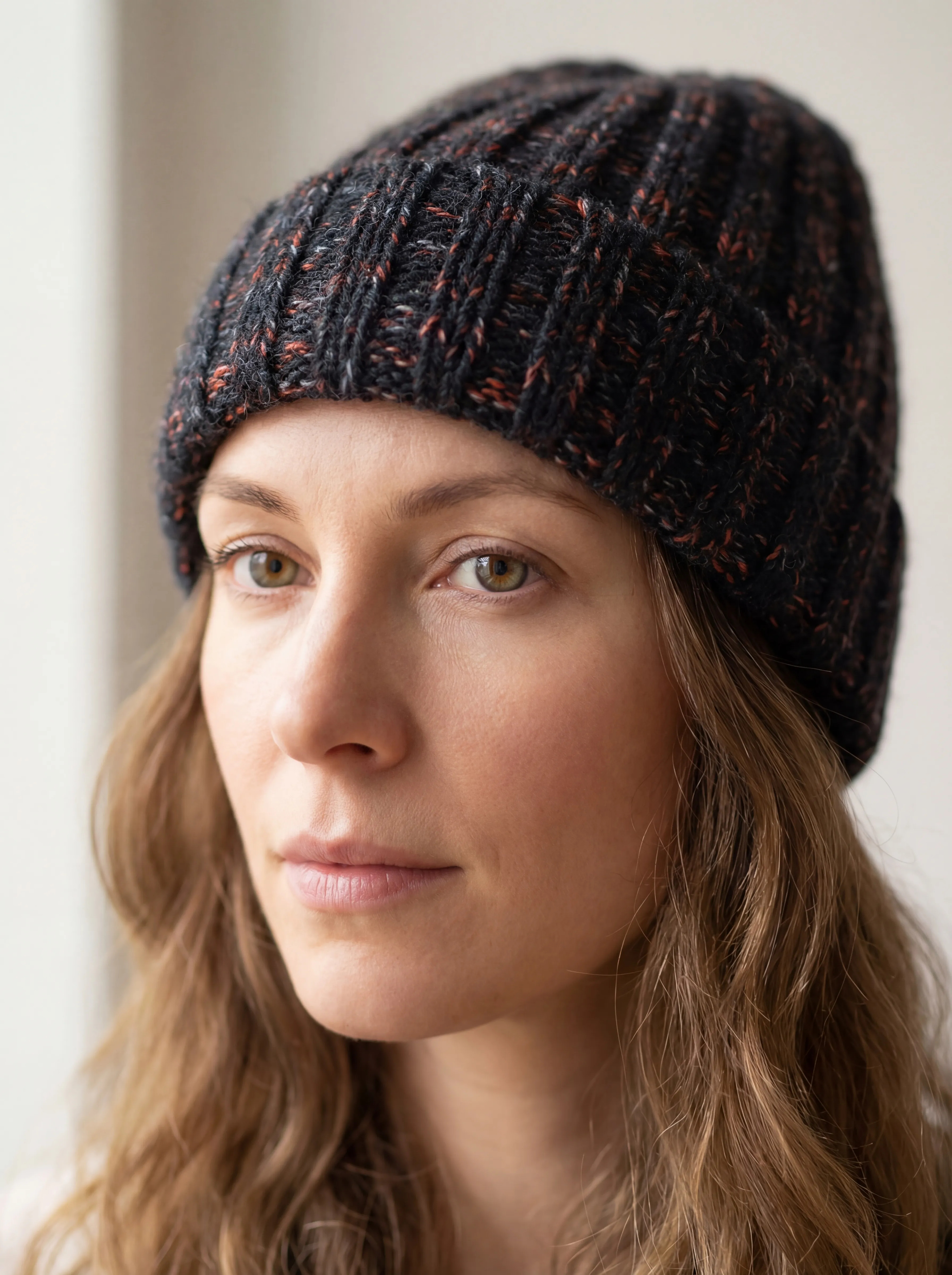 Woman wearing chunky ribbed yak wool hat in mottled black and pink