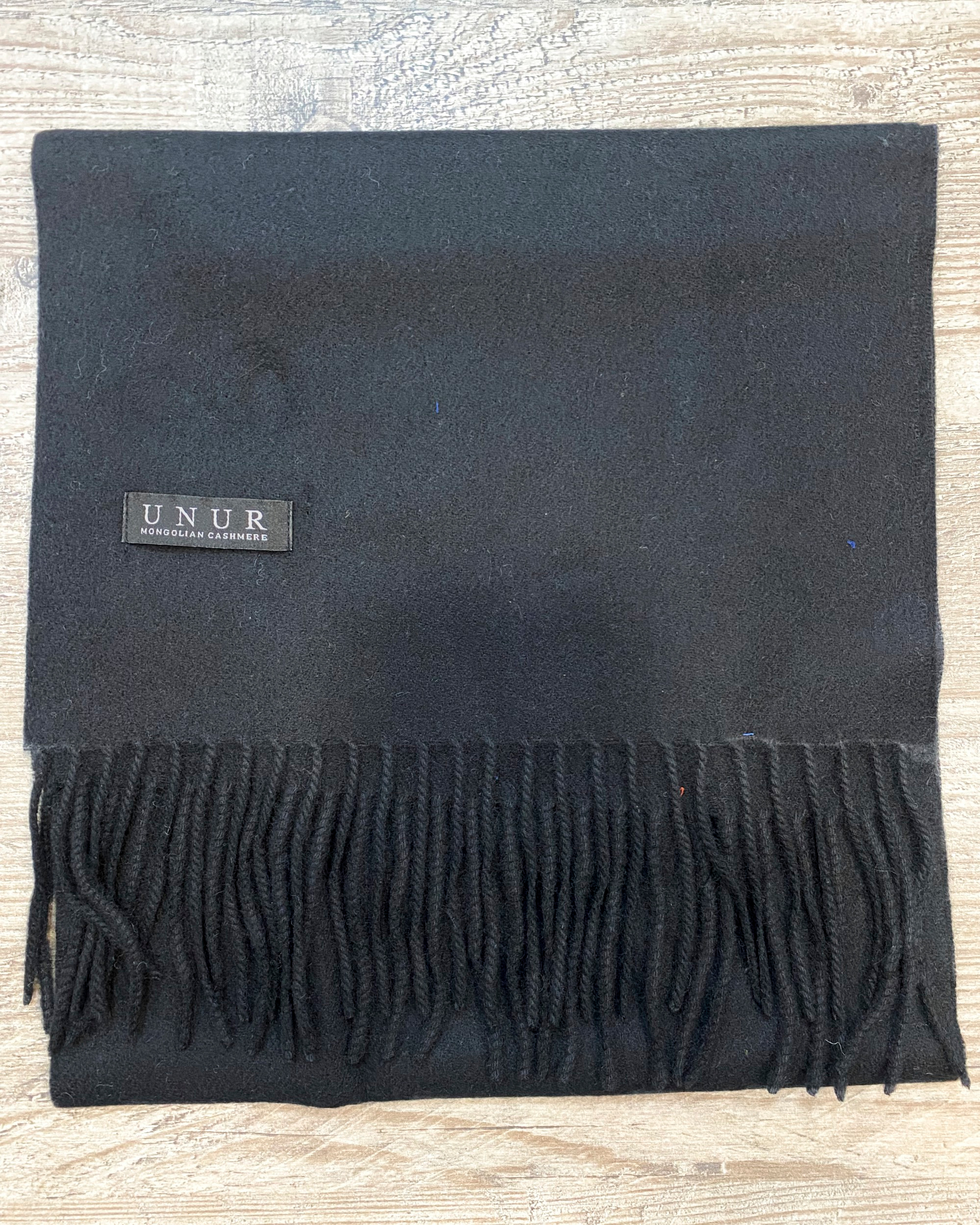 Lay-flat close up of black unisex woven cashmere scarf with tassles