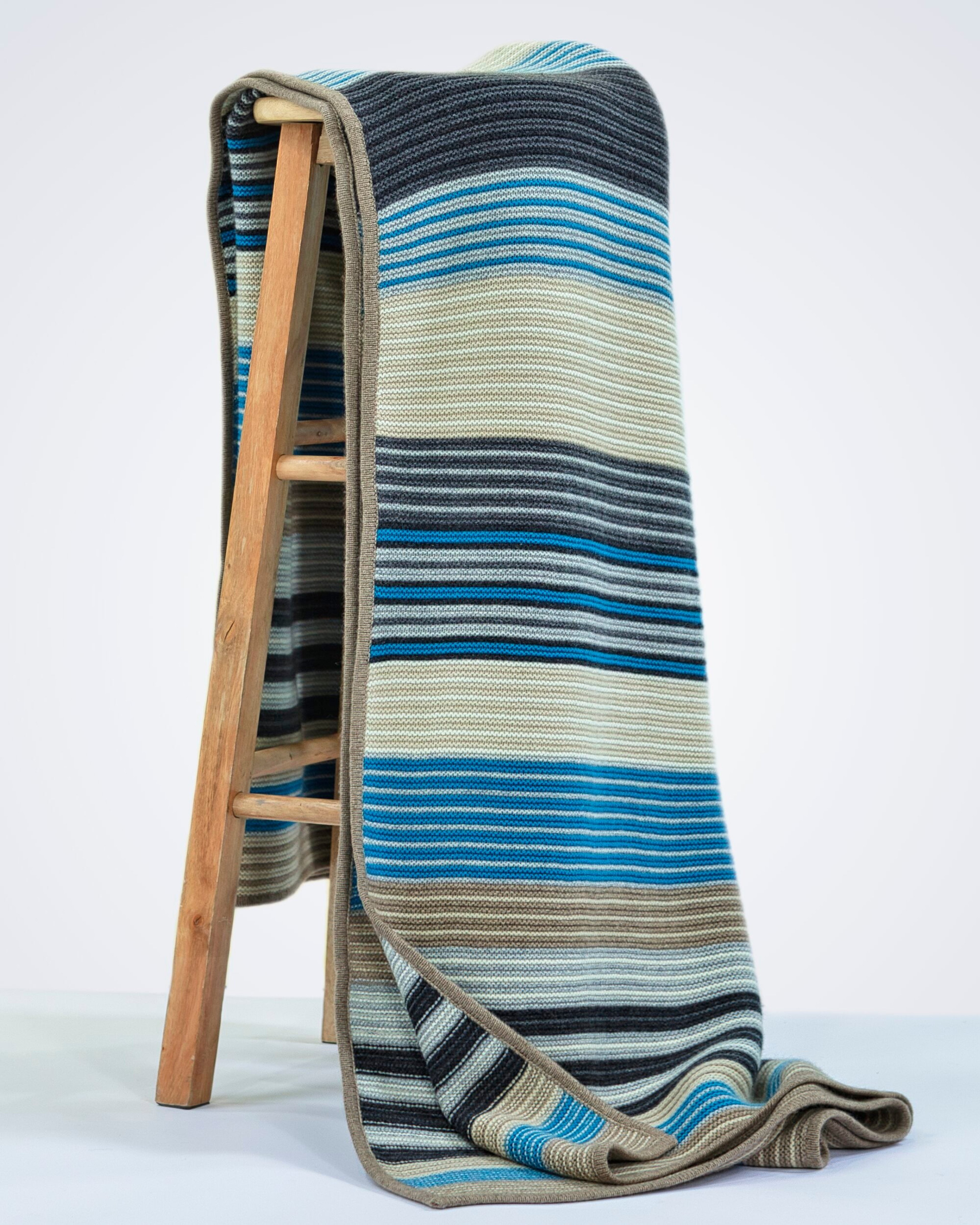 Soft cashmere rib-knit blanket in blue, draped over a chair