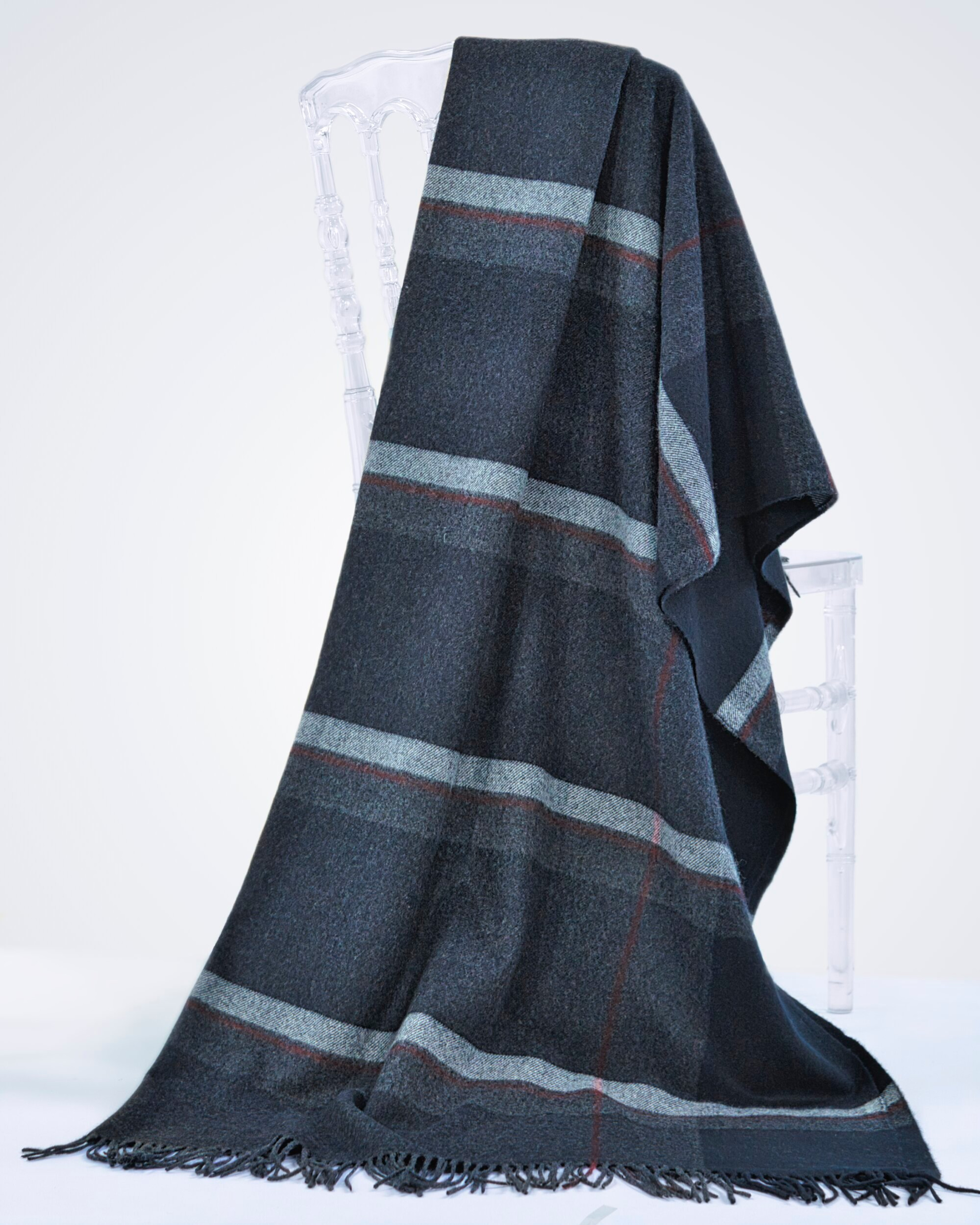 Charcoal cashmere checked pattern blanket with tassels, draped over a chair