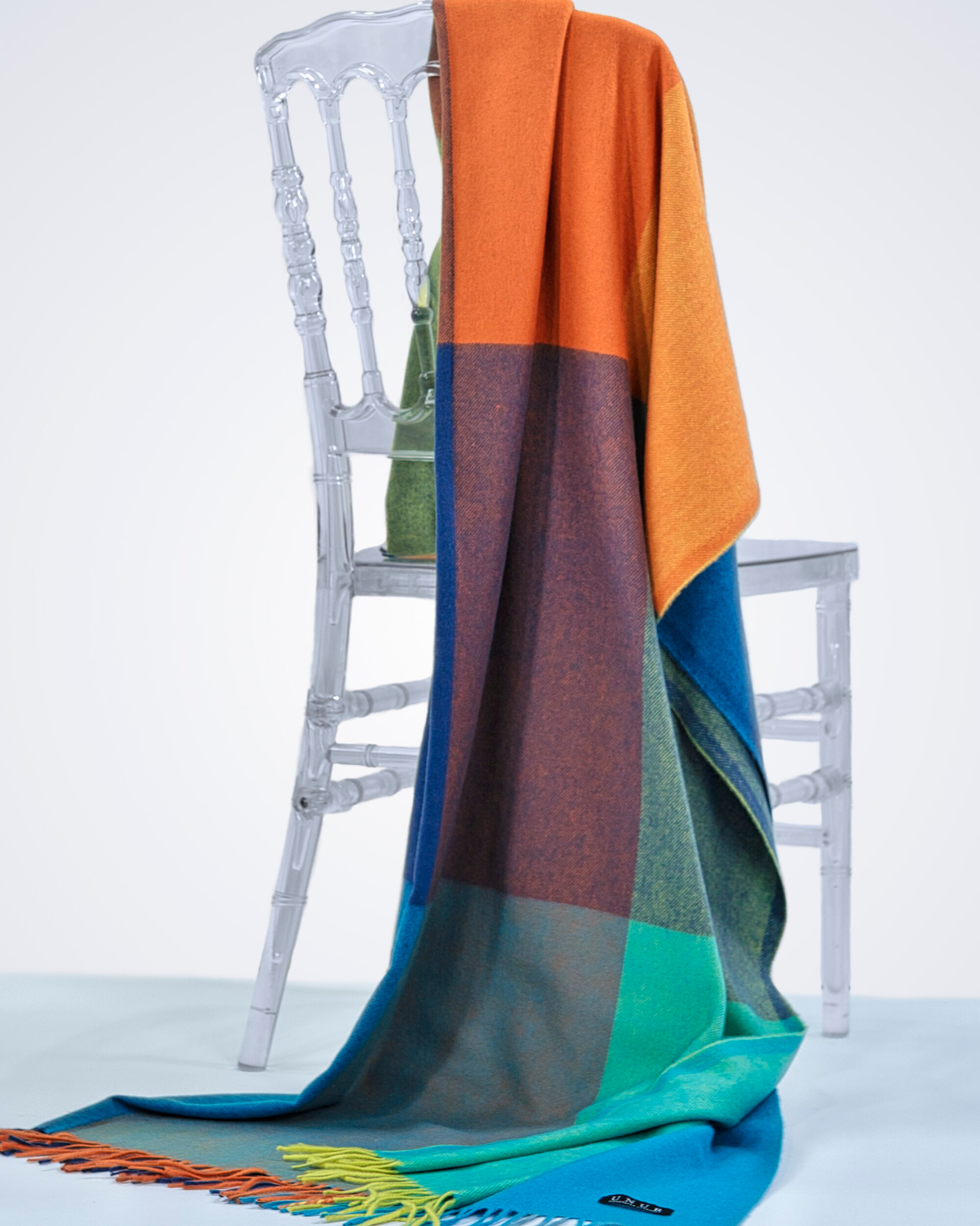 Multi-coloured cashmere checked pattern blanket with tassels, draped over a chair