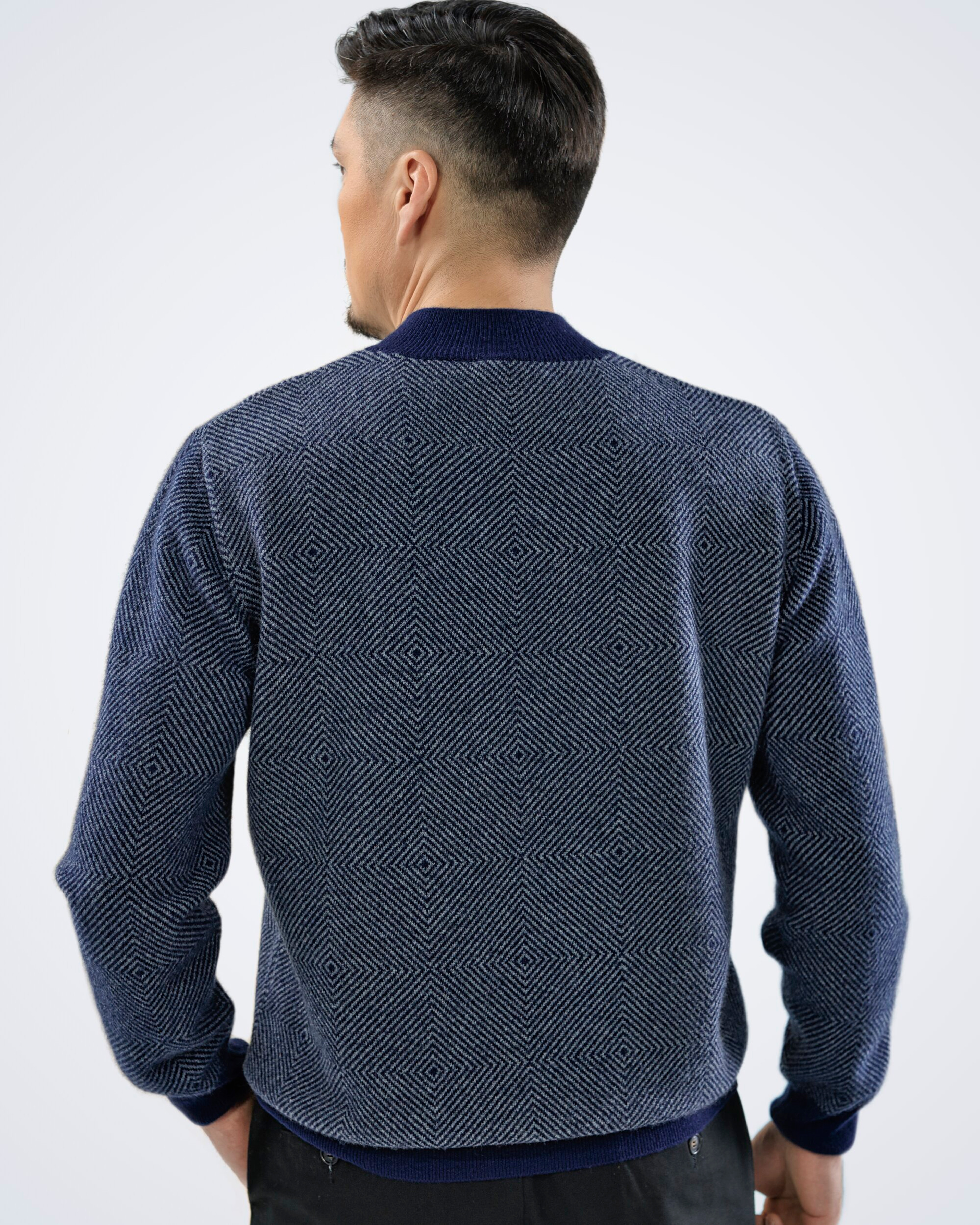 Unur model wearing a men's cashmere high neck jumper with diamond pattern in navy blue, back view