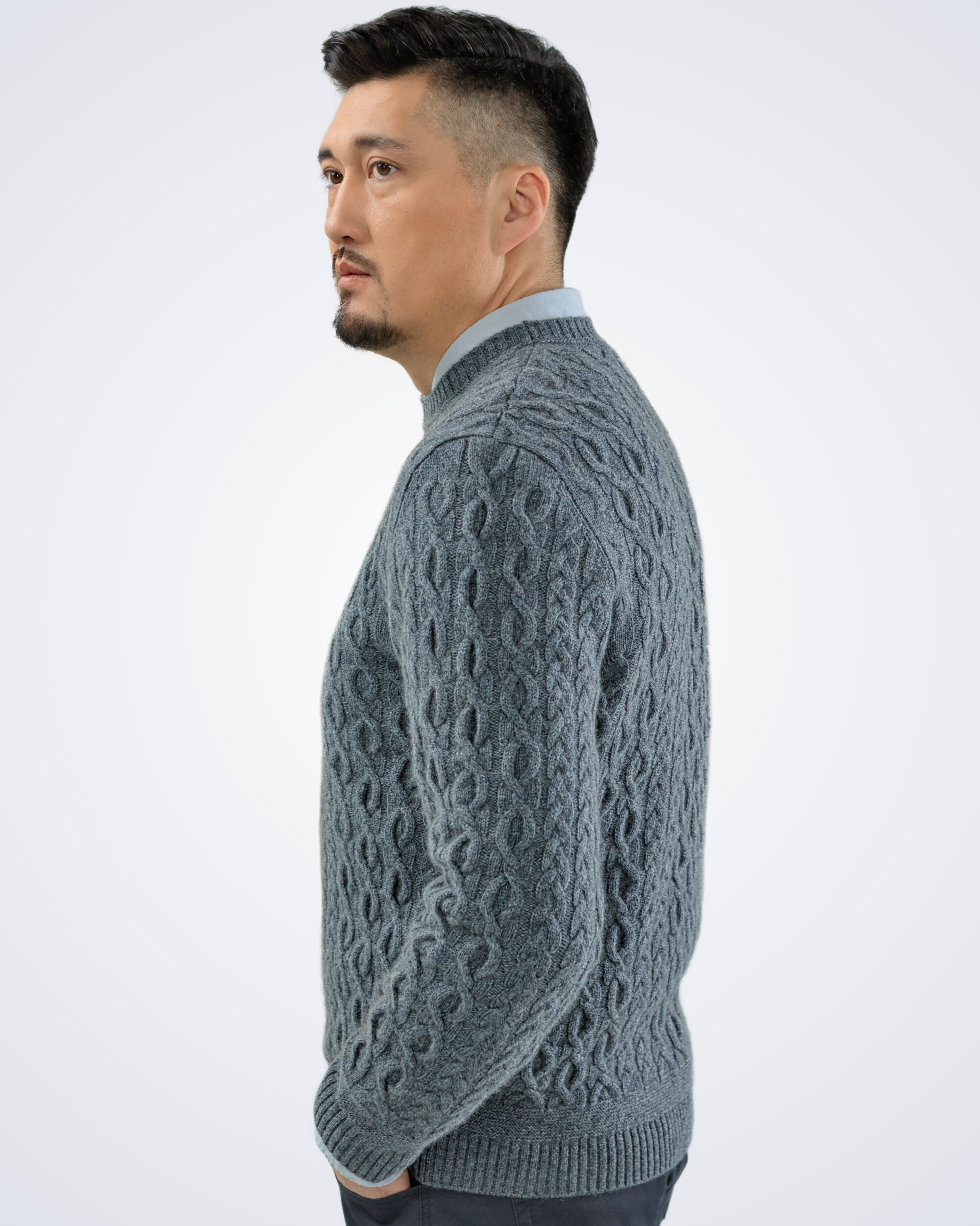 Unur model wearing a grey men's cashmere round neck cable knit jumper, rear view