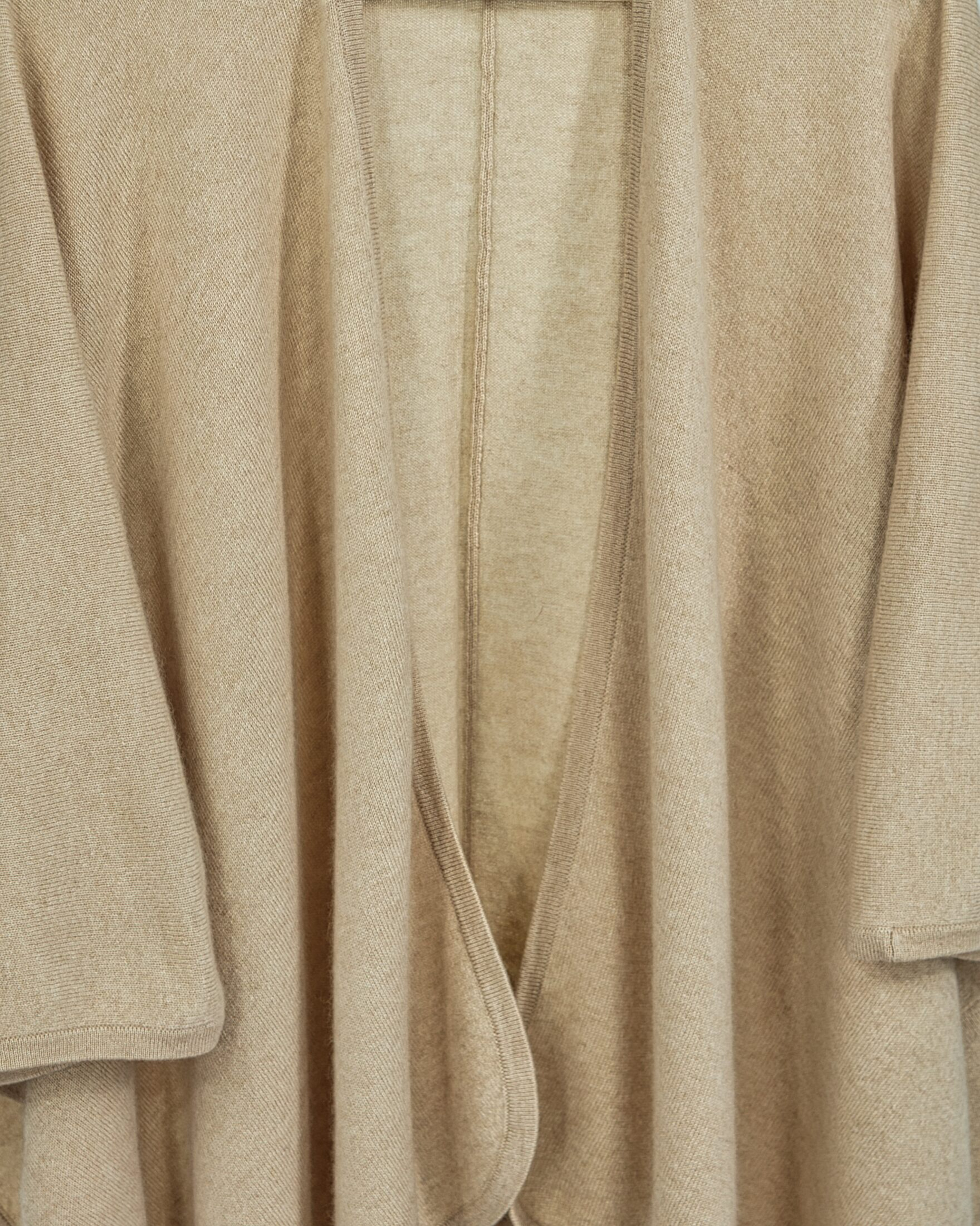 Close up of natural beige cashmere cape with a fluid silhouette