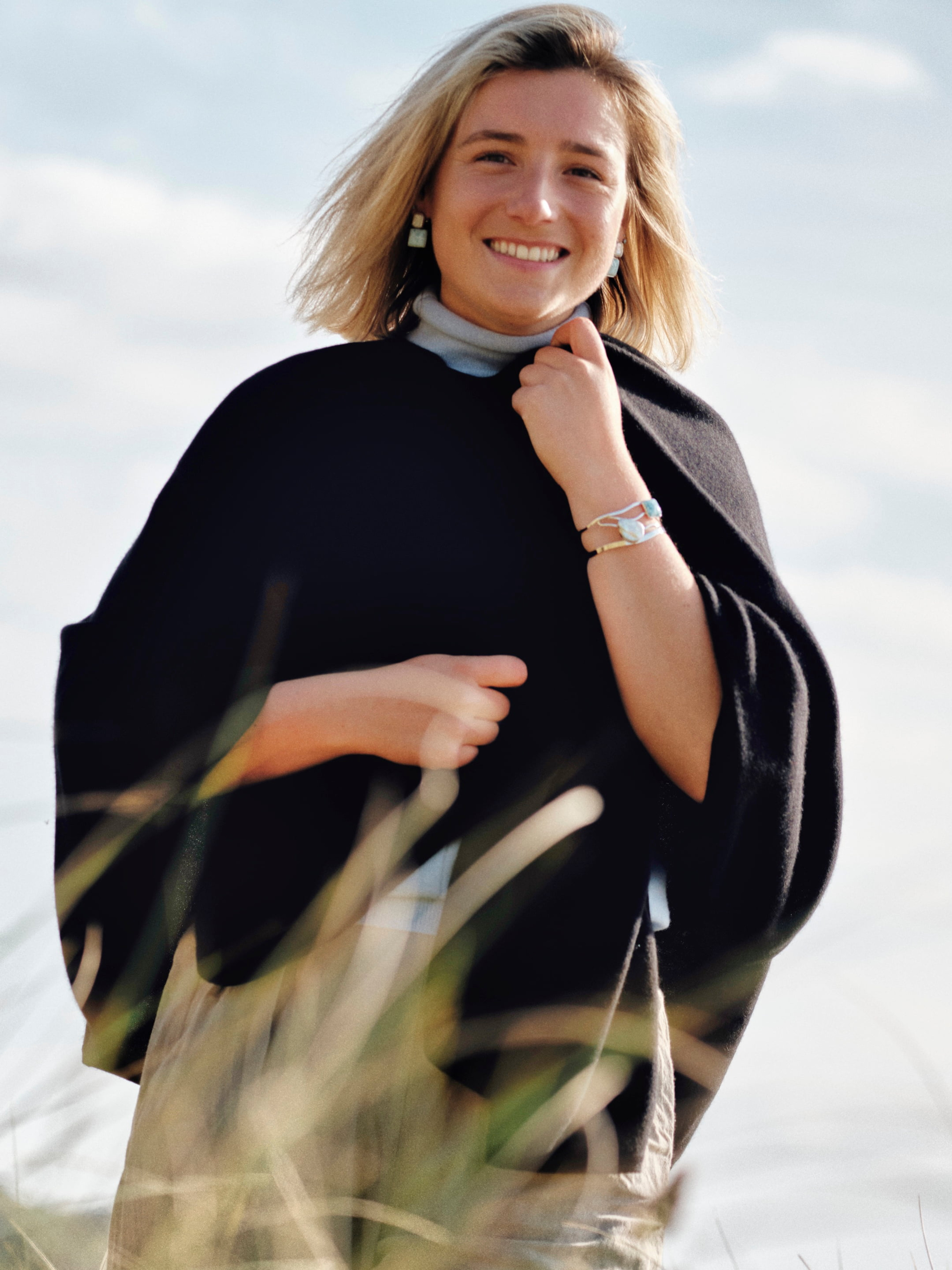 Model outdoors wearing a black cashmere cape with elegant draping