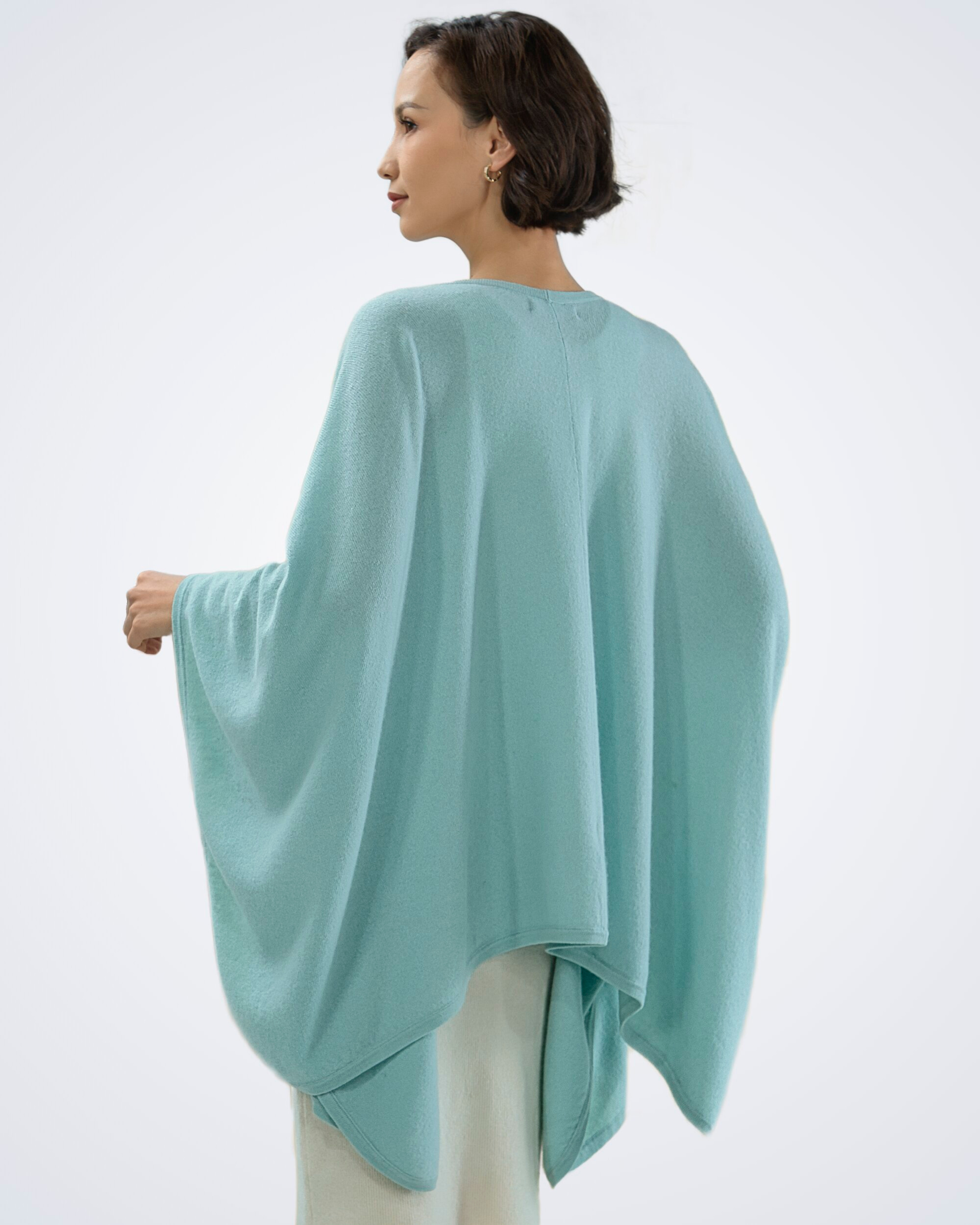 Unur model wearing a mint green cashmere cape, back view