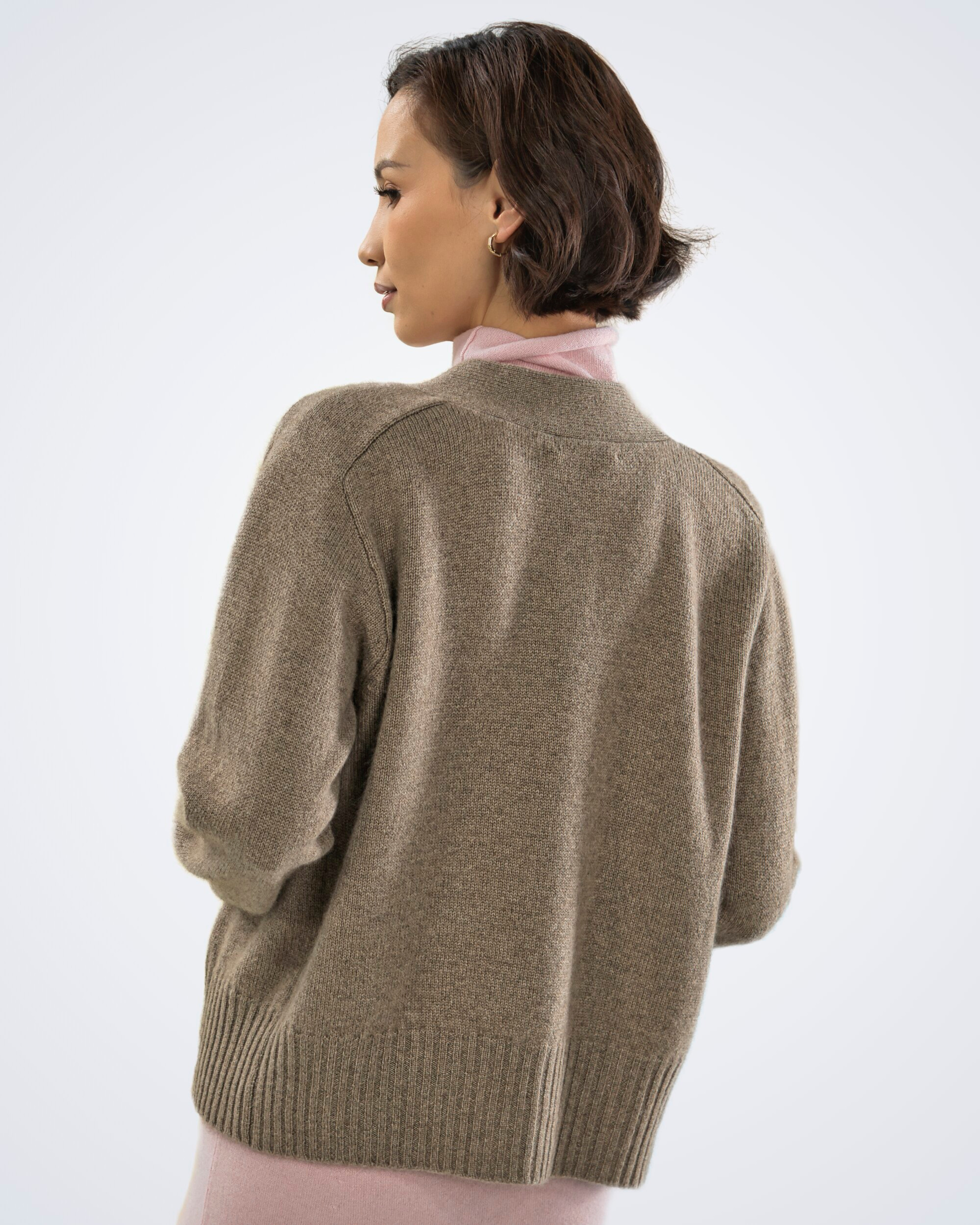Unur model wearing a natural brown cashmere classic buttoned cardigan, showing the back