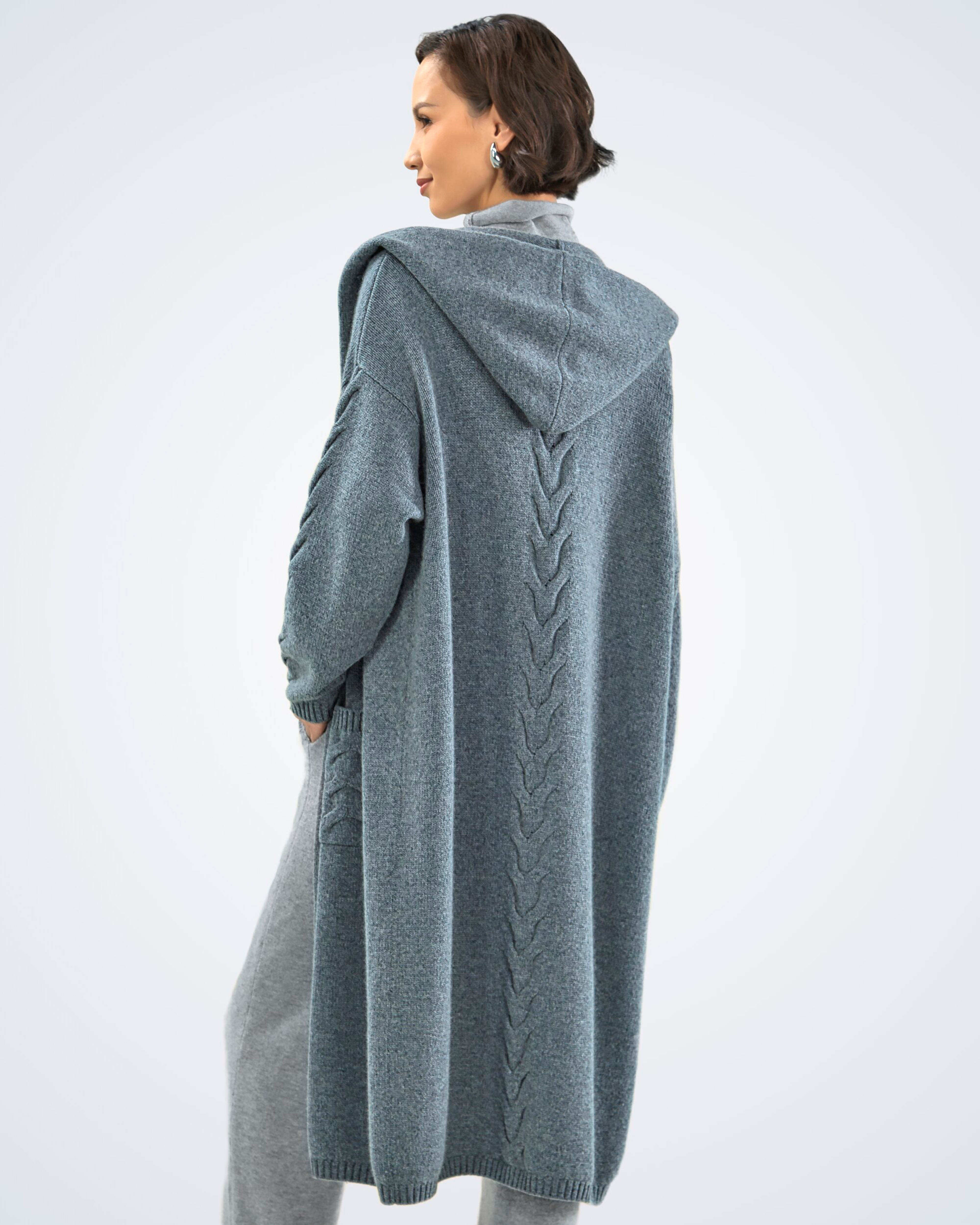 Unur model wearing a dark grey cable knit cashmere long cardigan with hoodie, rear view