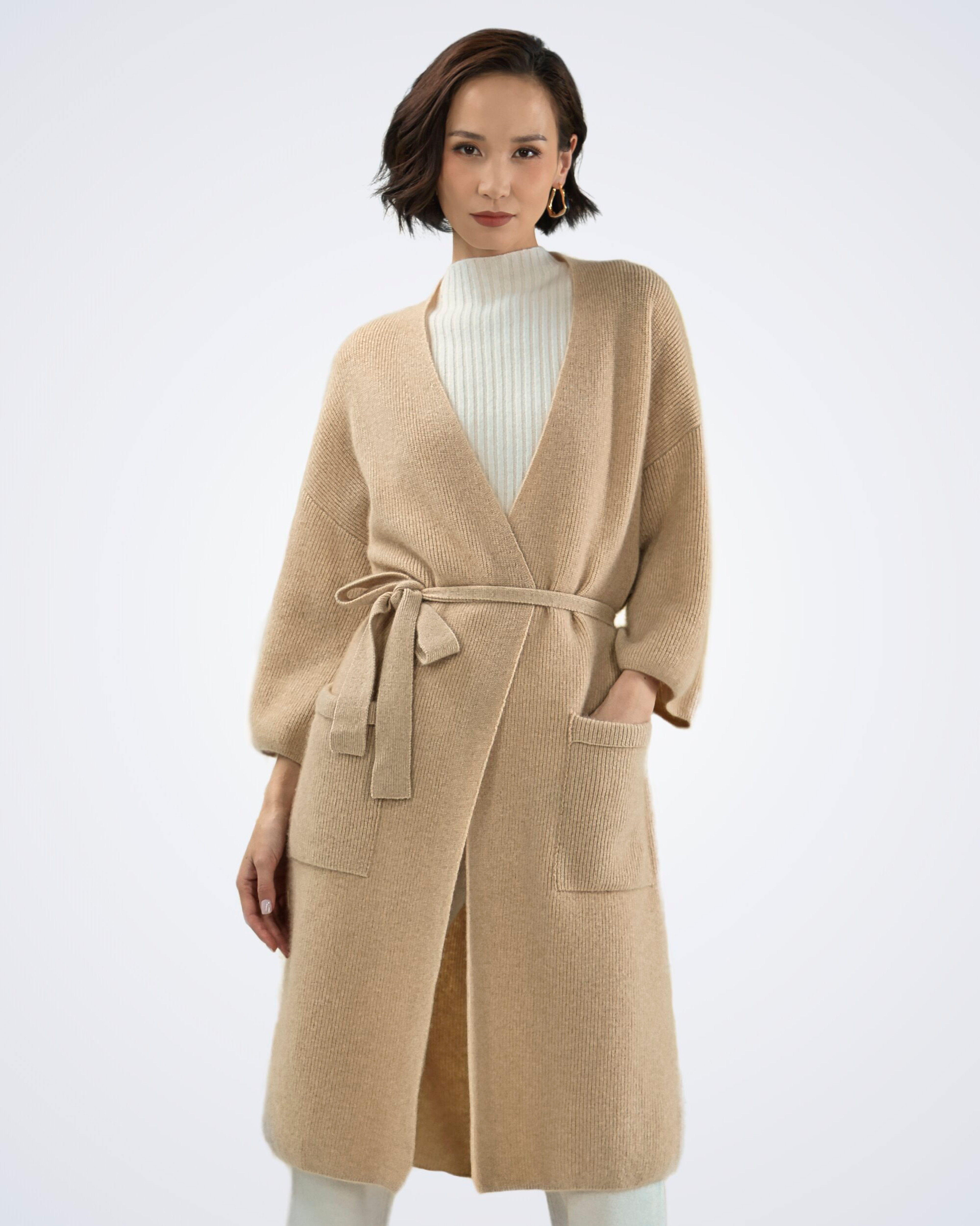 Unur model wearing a natural beige ribbed cashmere long cardigan coat with a tie belt