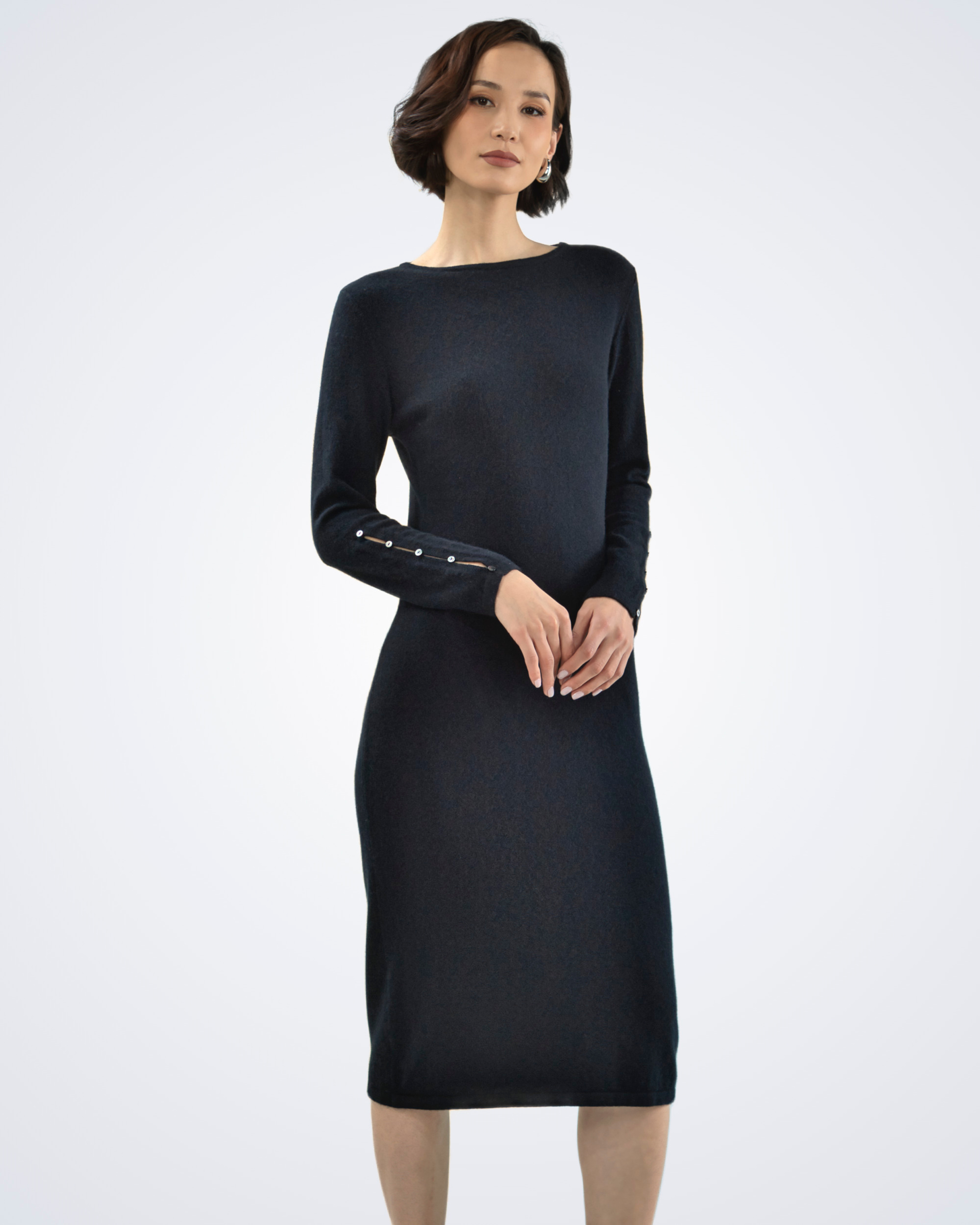 Unur model wearing a black cashmere midi dress with buttoned sleeves and a boat neckline